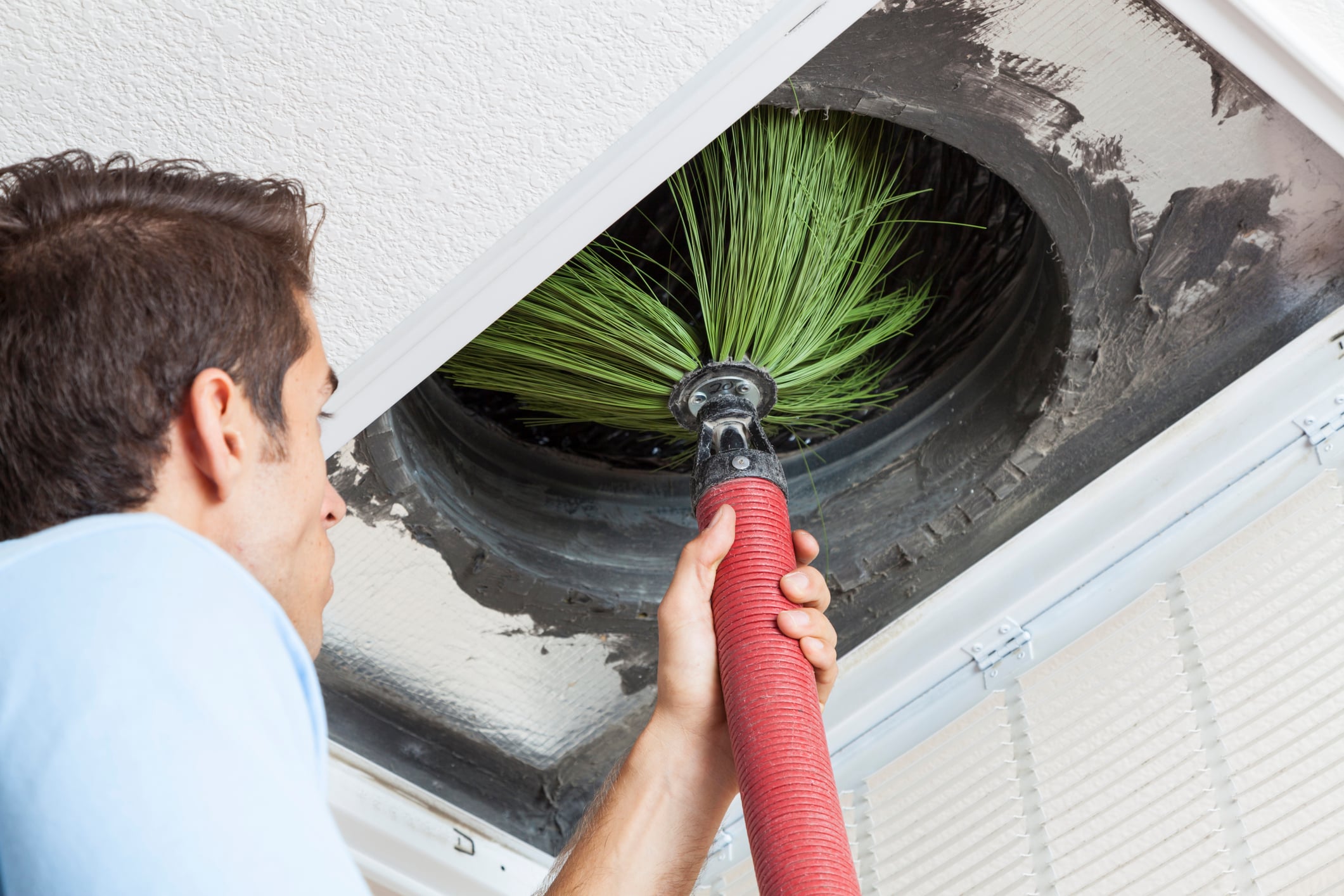 HVAC specialist inspecting interior ductwork with tools to identify heavy dust accumulation