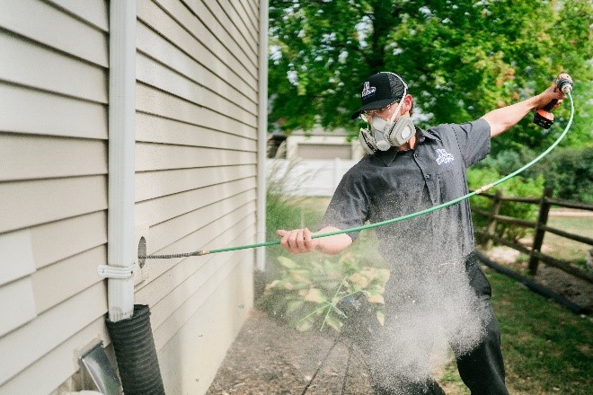 Technician cleaning clogged dryer vent behind laundry machines in Tampa home
